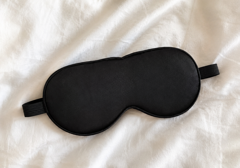 Black sleep mask on a white fabric background