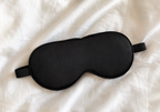 Black sleep mask on a white fabric background