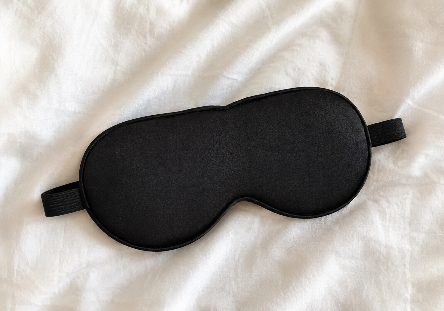 Black sleep mask on a white fabric background