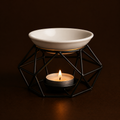 Ceramic bowl on a geometric black stand with a lit candle inside, against a dark background
