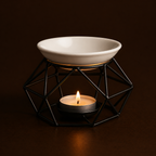 Ceramic bowl on a geometric black stand with a lit candle inside, against a dark background