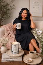 Woman sitting on a couch holding a mug with decorative items around her.