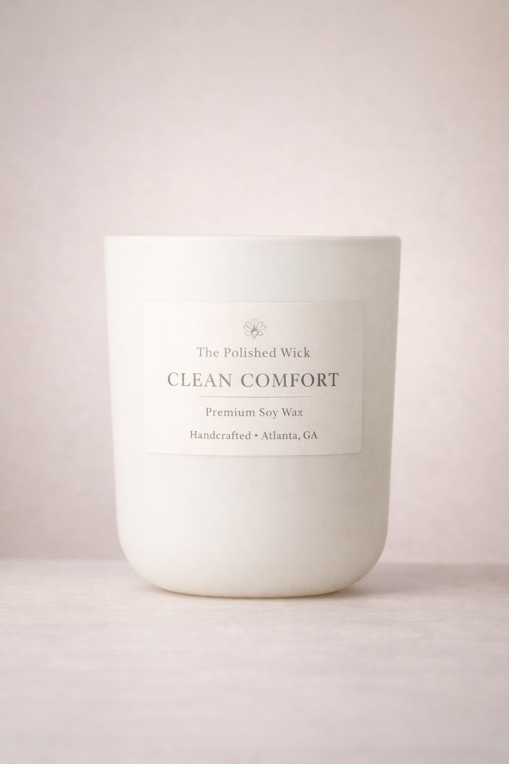 White candle labeled 'Clean Comfort' by 'The Polished Wick' on a light pink background