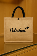 Beige tote bag with 'Polished' text on a wooden surface