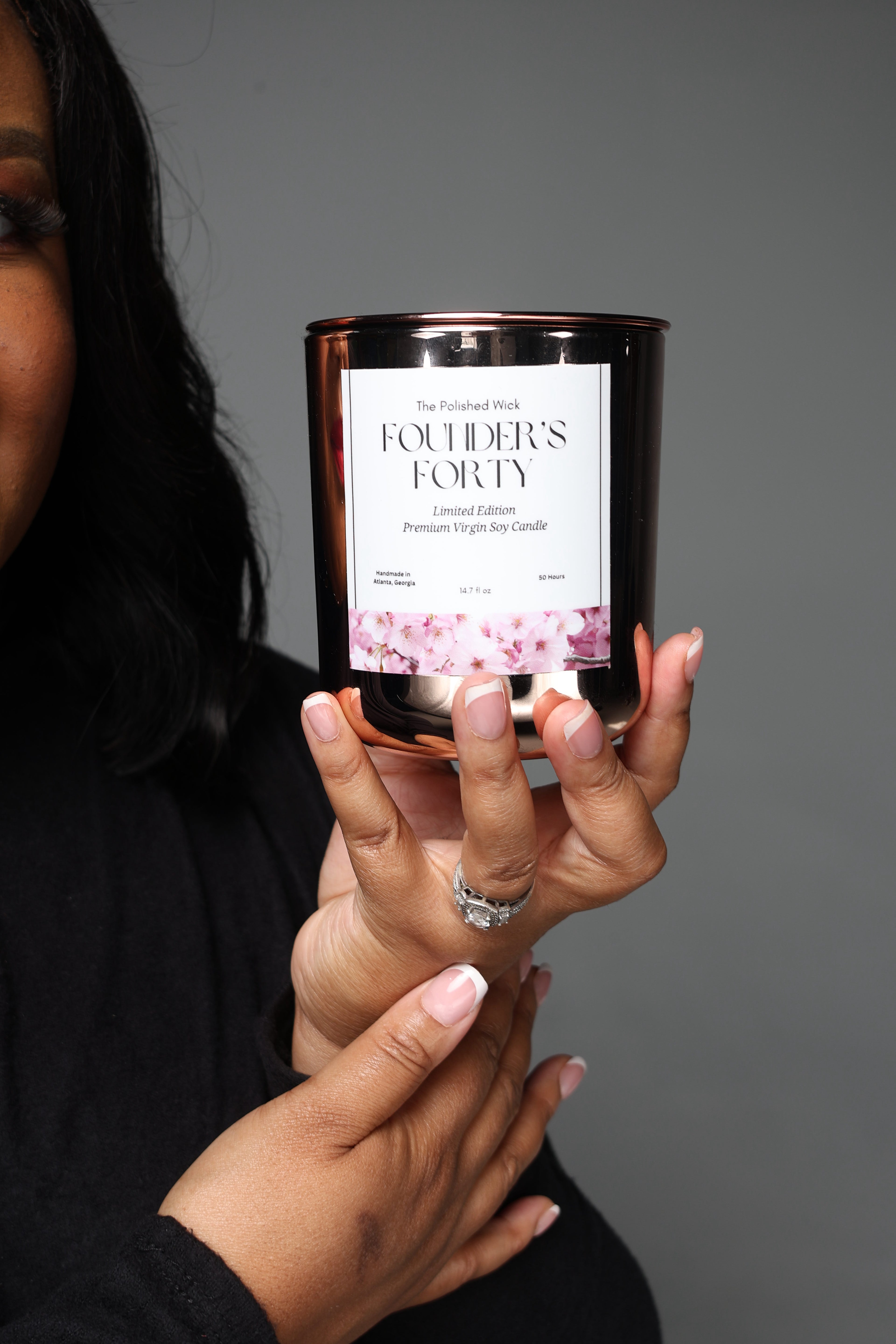Person holding a candle labeled 'Founder's Forty' against a gray background