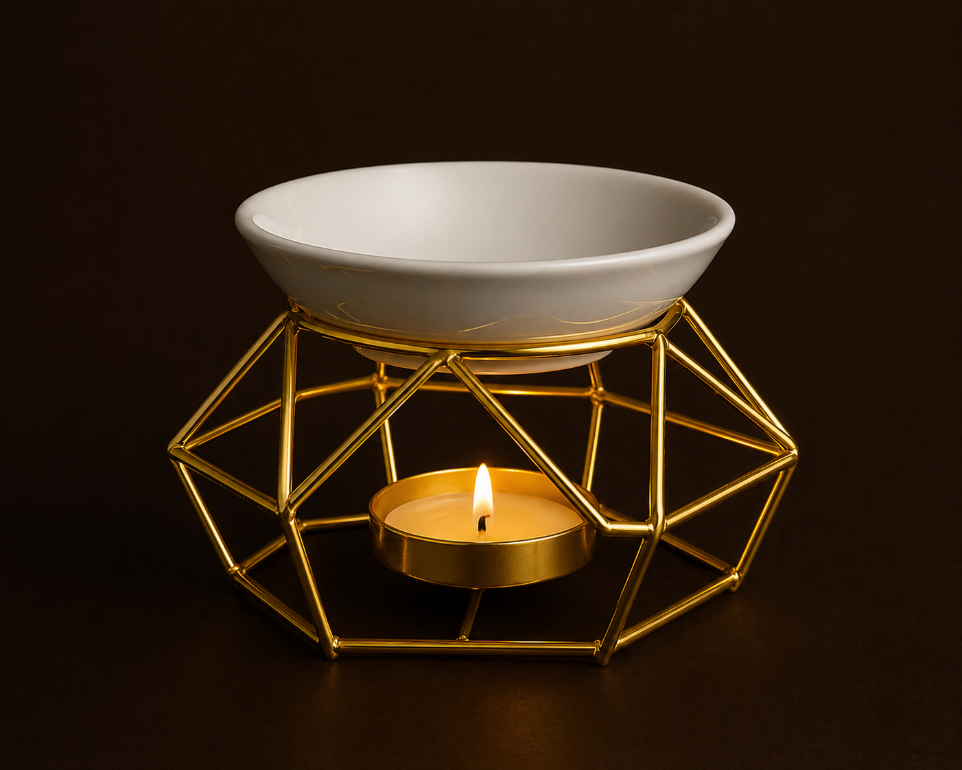 White ceramic bowl on a gold geometric stand with a lit candle inside, against a dark background