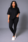 Woman wearing a black outfit with white shoes on a gray background