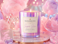 Candle labeled 'Sugar Glow' from The Polished Wick Candle Company on a pink and purple cotton candy background.
