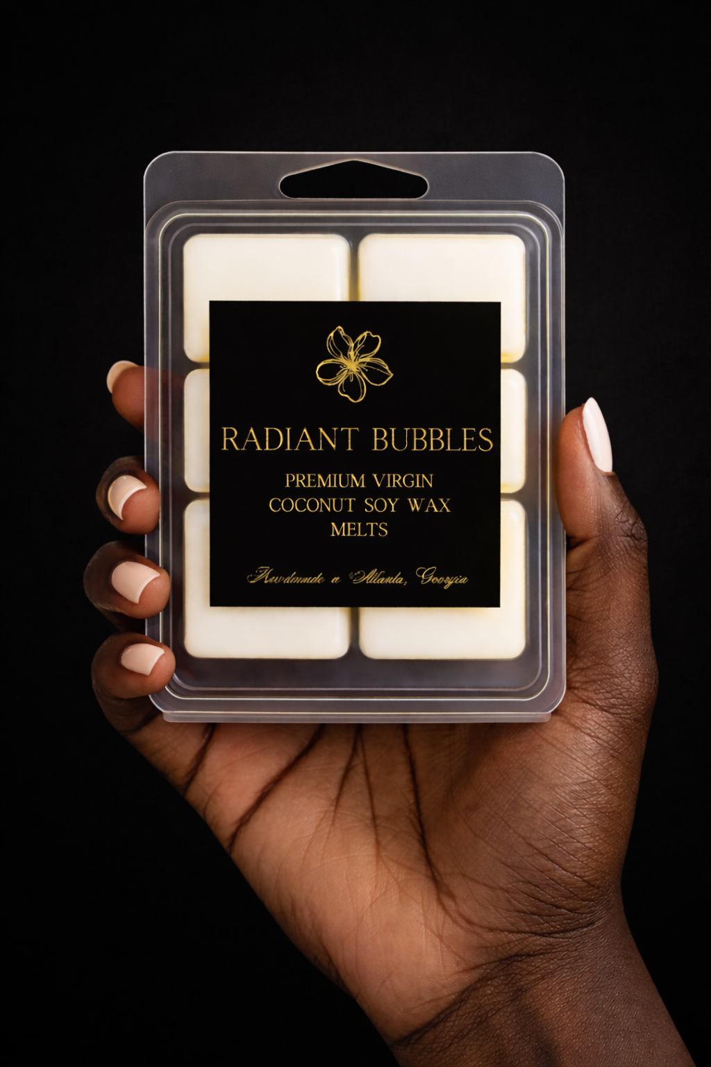 Hand holding a package of 'Radiant Bubbles' wax melts against a black background