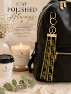Black backpack with 'Stay Polished Always' keychain, candle, and coffee cup on a neutral background.