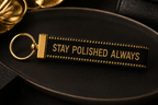 Black keychain with gold text 'Stay Polished Always' on a dark background