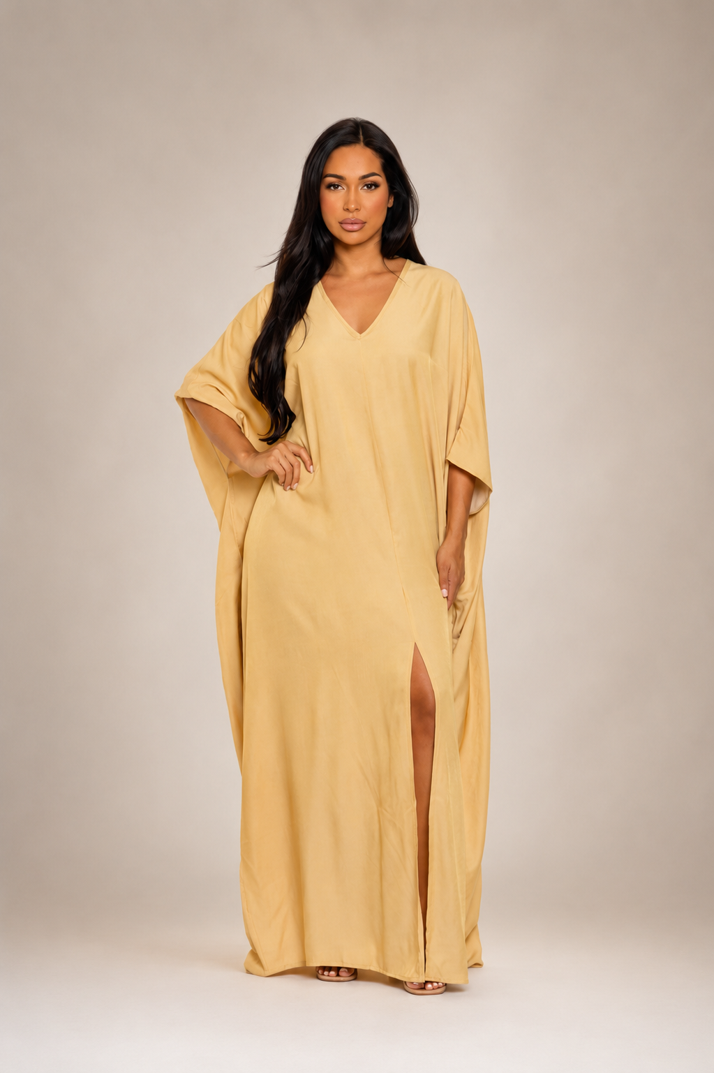 Woman wearing a yellow caftan dress against a neutral background