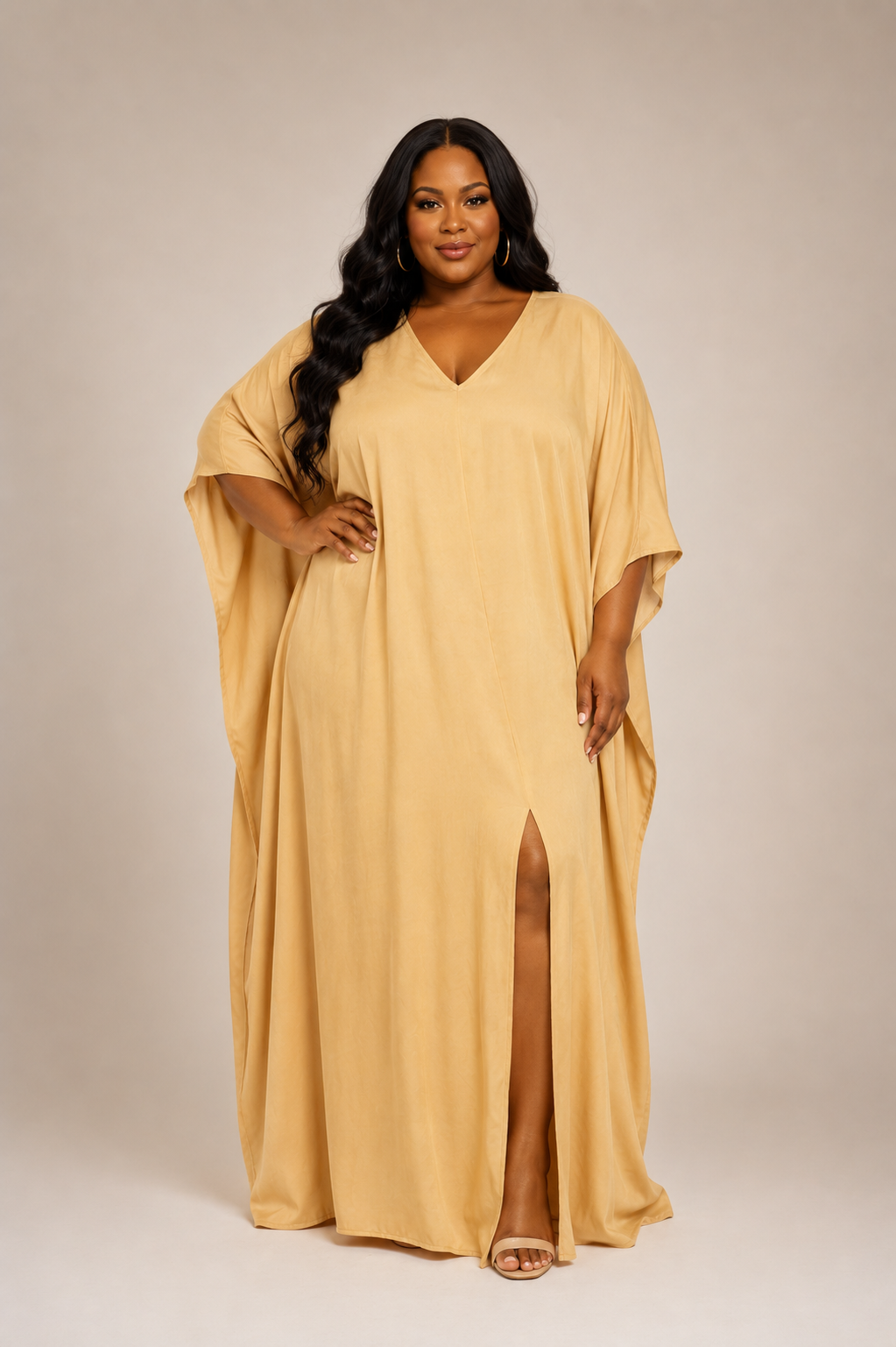 Woman wearing a beige maxi dress with a slit on a plain background