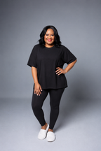 Woman wearing a black outfit with white shoes on a gray background